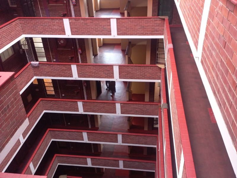 An elevated view of an open-air apartment building atrium featuring multi-level brick walkways and stairwells.