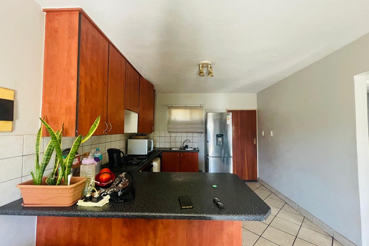 A functional kitchen featuring laminate cabinetry, a breakfast bar, and tiled flooring, offering a practical layout with potential for modern updates.