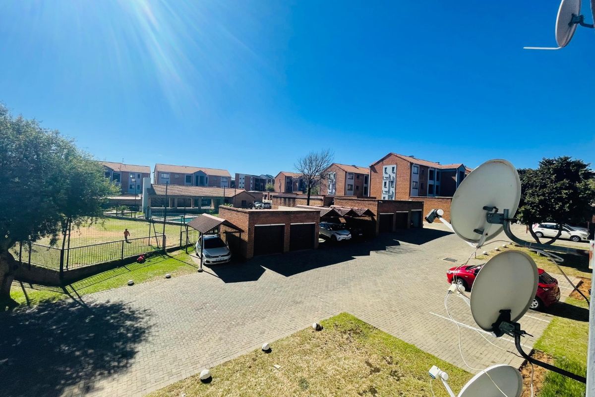 Elevated view of the apartment complex grounds, featuring brick garages, paved driveway, and communal outdoor space.