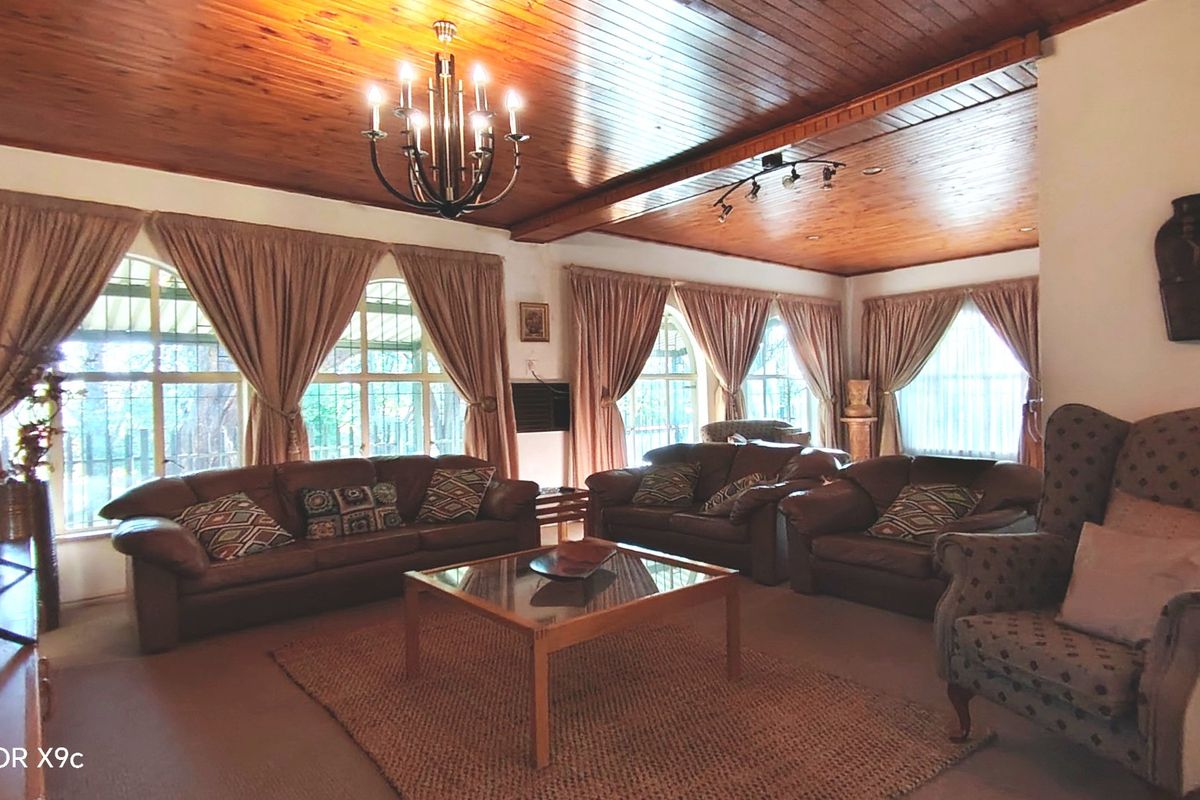 Spacious living room featuring a warm timber-clad ceiling, elegant arched windows, and a combination of chandelier and track lighting.