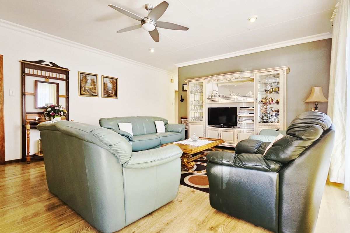 A comfortable living room featuring laminate flooring, a ceiling fan, and recessed lighting, providing a functional and well-lit space for relaxation.