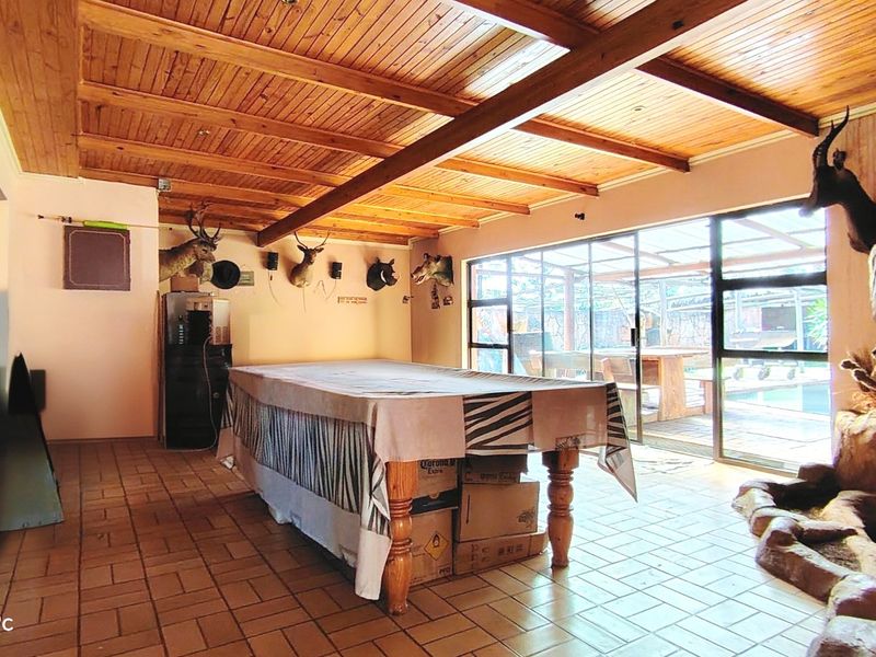 Spacious living area featuring a timber-clad ceiling, tiled flooring, and large sliding glass doors providing direct access to the outdoor patio and pool area.