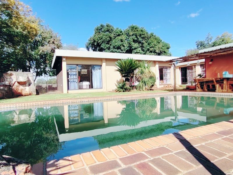 Outdoor pool area featuring a swimming pool with brick paving and a covered patio area adjacent to the main dwelling.