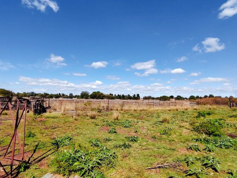 Expansive open farm land featuring perimeter fencing and natural vegetation, suitable for agricultural use or development.