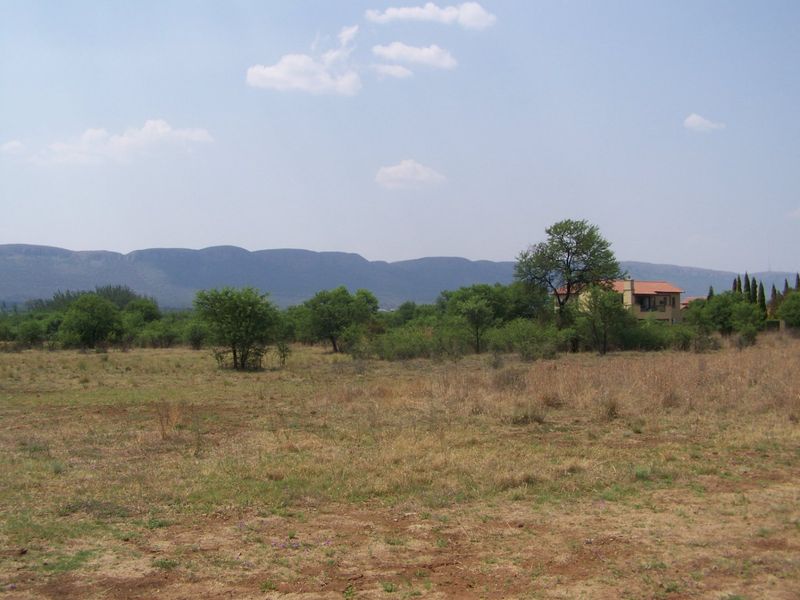 A scenic view of the vacant residential land featuring natural vegetation and a distant mountain range backdrop.