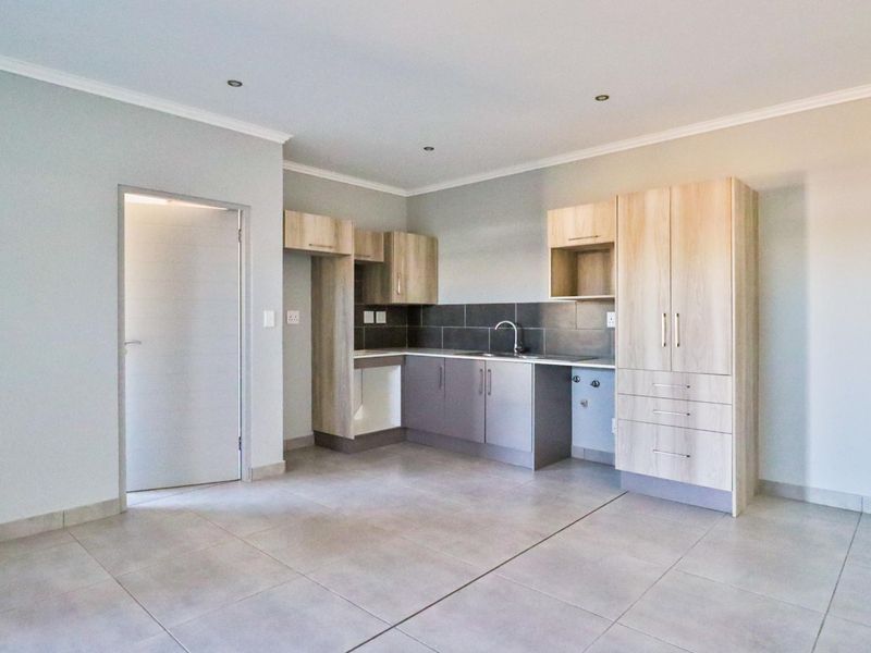 A clean, modern kitchen featuring light wood-tone cabinetry, dark tiled backsplash, and neutral floor tiles, offering a functional and well-maintained space.