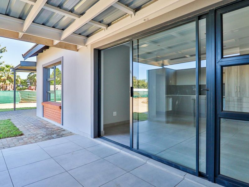 A clean, covered patio area featuring modern tiled flooring and large sliding glass doors providing seamless access to the interior living space.
