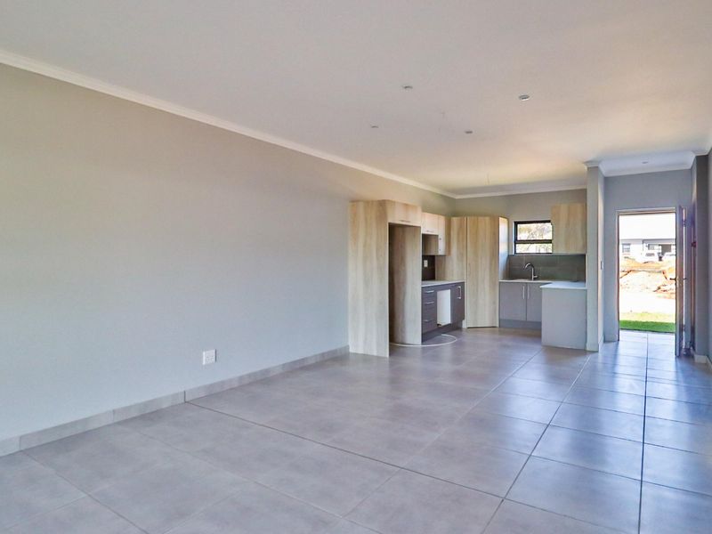 An open-plan living and kitchen area featuring modern cabinetry, tiled flooring, and direct access to the exterior.