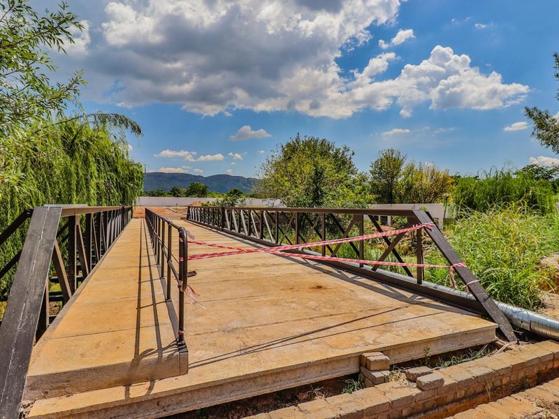 A metal pedestrian bridge under construction, featuring safety railings and currently cordoned off with warning tape.