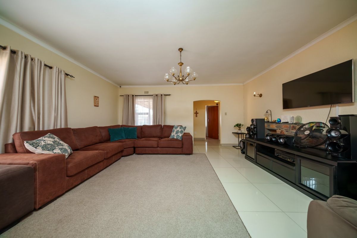 Spacious living room featuring tiled flooring, a stone-clad feature wall, and an arched doorway leading to the rest of the home.