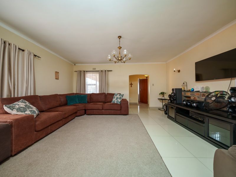 Spacious living room featuring tiled flooring, a stone-clad feature wall, and an arched doorway leading to the rest of the home.