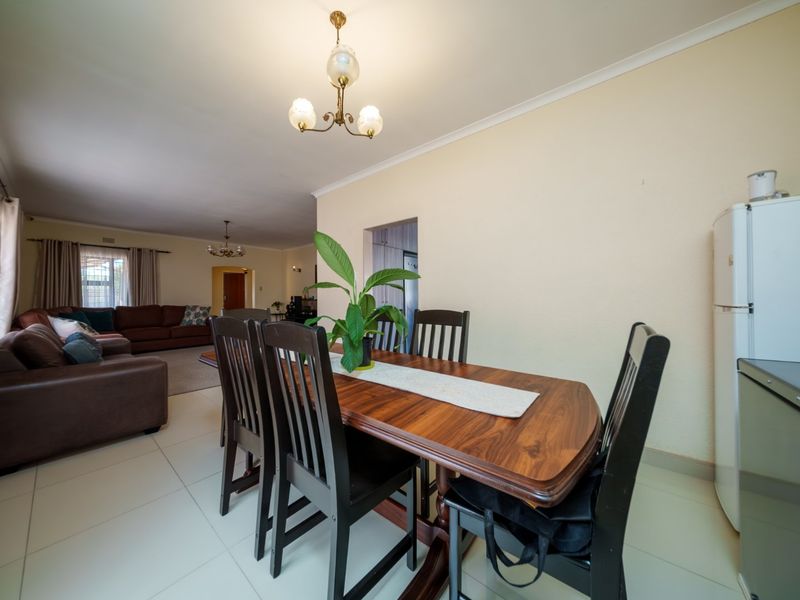 Spacious open-plan living and dining area featuring neutral tiled flooring, coved cornicing, and a seamless flow between the dining space and lounge.