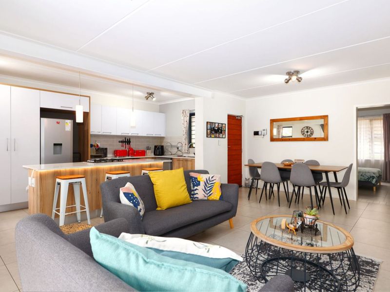 Spacious open-plan living area featuring a modern kitchen with a central island, stone countertops, and tiled flooring throughout.