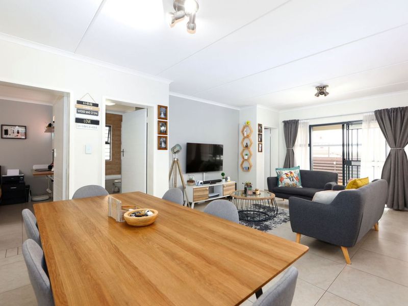 An open-plan living and dining area featuring tiled flooring, neutral walls, and a sliding glass door leading to an outdoor space.