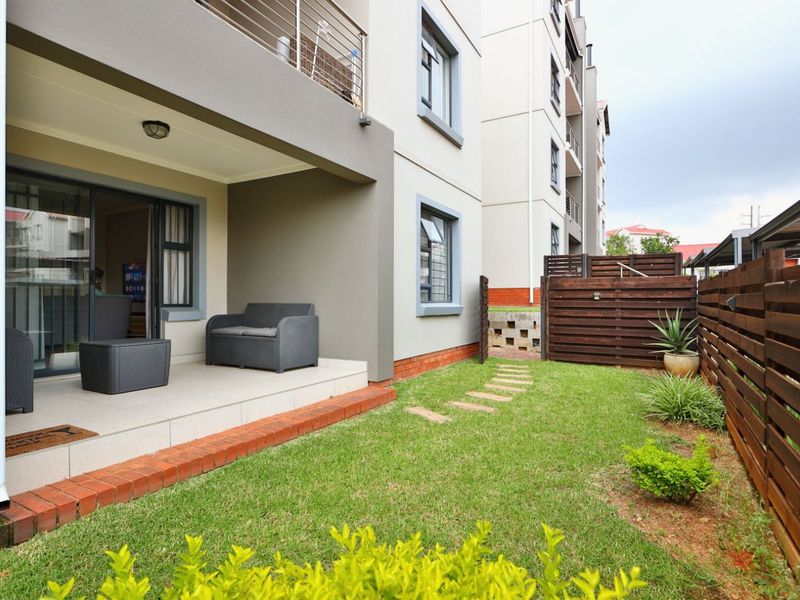 A ground floor townhouse unit featuring a covered tiled patio, private garden area, and timber privacy fencing.