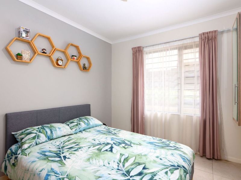 A well-maintained bedroom featuring tiled flooring, a built-in wardrobe, and a window fitted with security bars for added peace of mind.