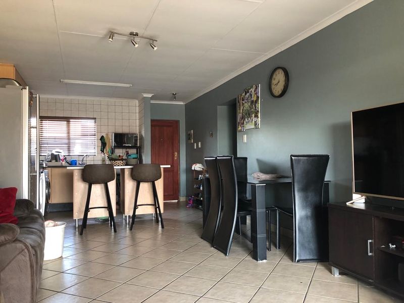 Open-plan living and dining area featuring tiled floors, a functional kitchen island, and direct access to the main entrance.