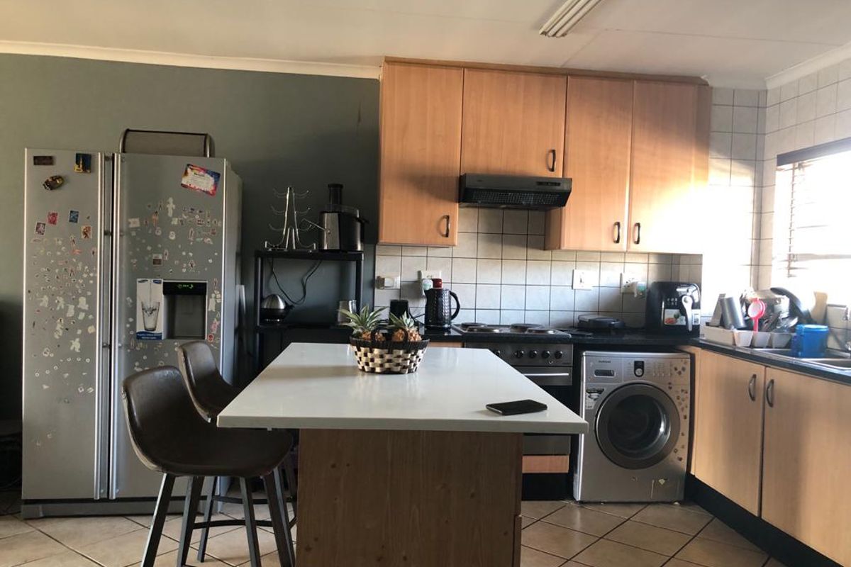 A functional kitchen featuring built-in wooden cabinetry, a tiled backsplash, an electric stove with extractor fan, and a central kitchen island.