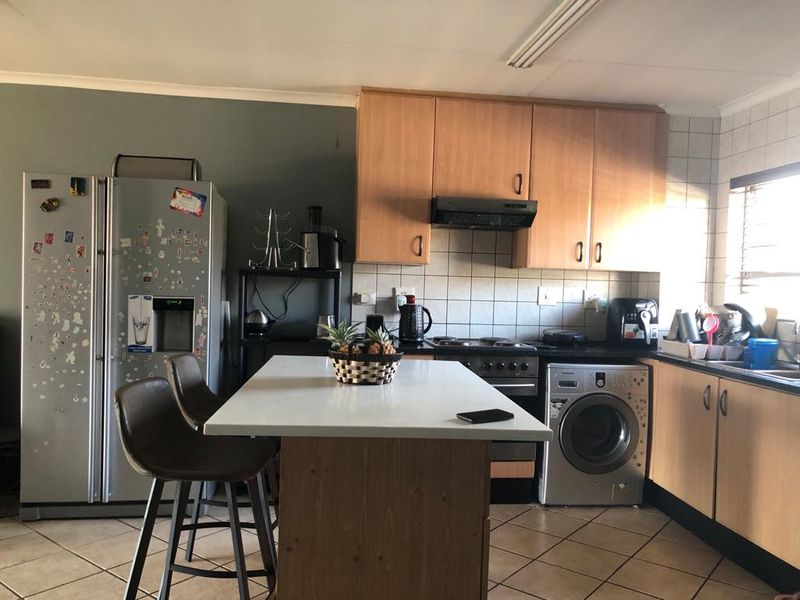 A functional kitchen featuring built-in wooden cabinetry, a tiled backsplash, an electric stove with extractor fan, and a central kitchen island.