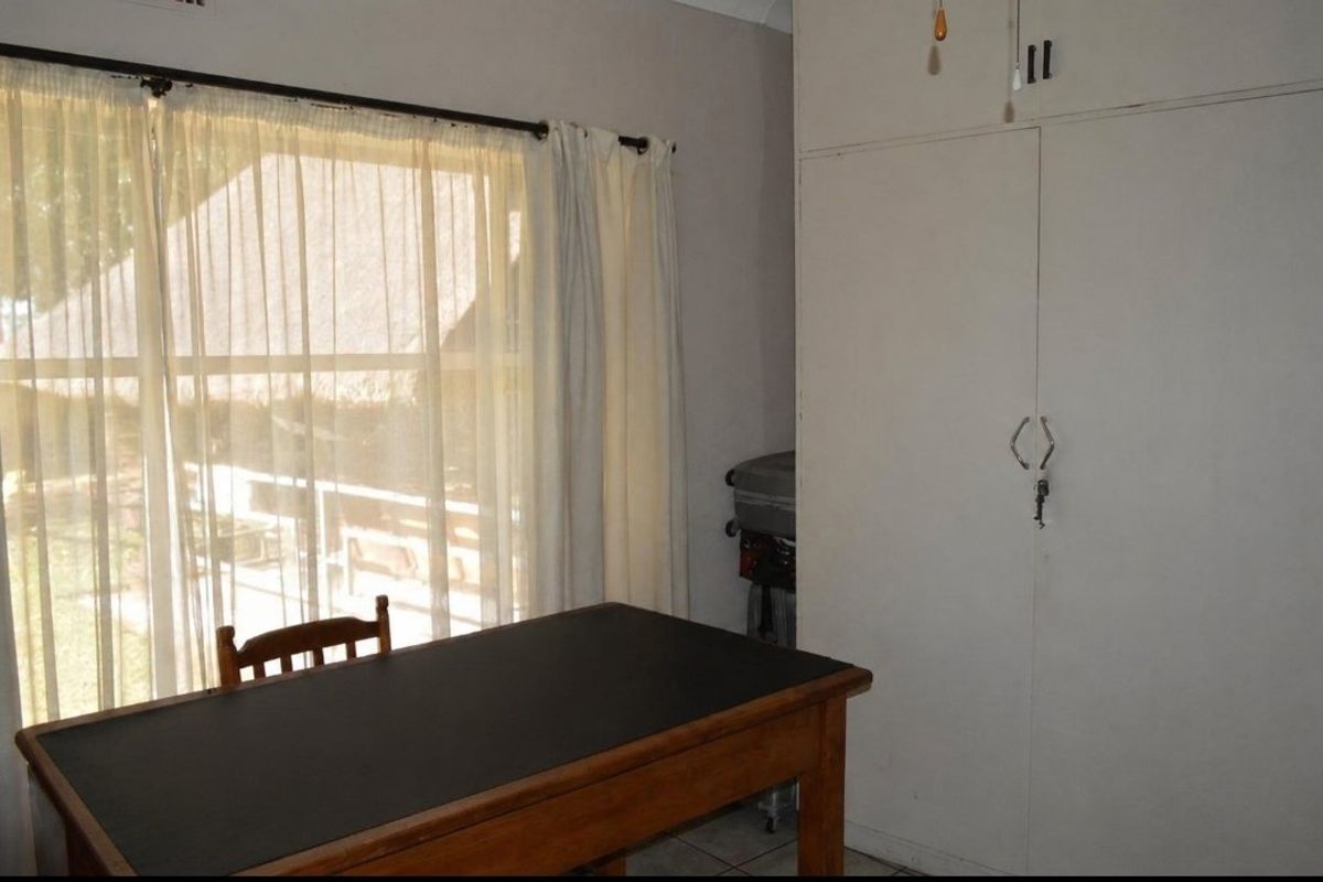 A bedroom featuring built-in cupboards and natural light from a large window.