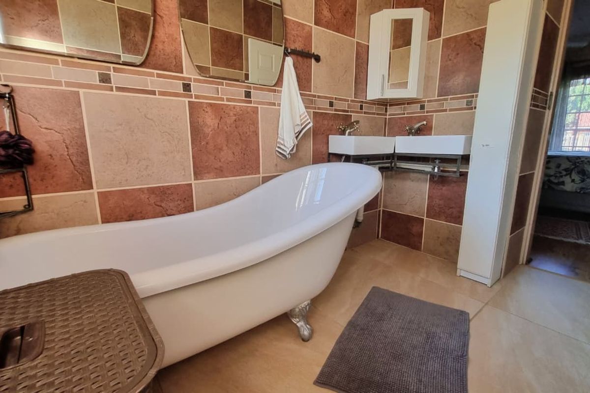 Bathroom featuring a classic freestanding clawfoot bathtub, dual wall-mounted basins, and decorative ceramic wall tiles.