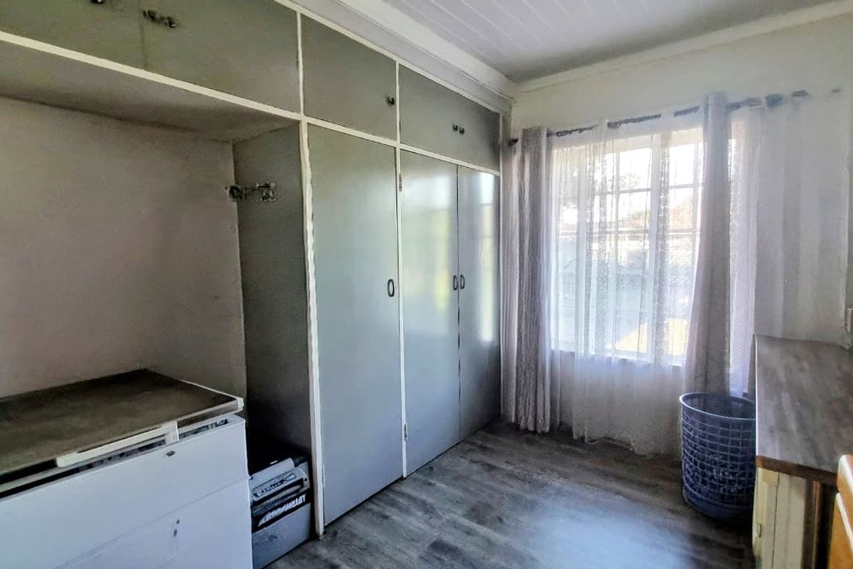 A bedroom featuring built-in cupboards, laminate flooring, and a timber ceiling, offering a functional space ready for modernization.