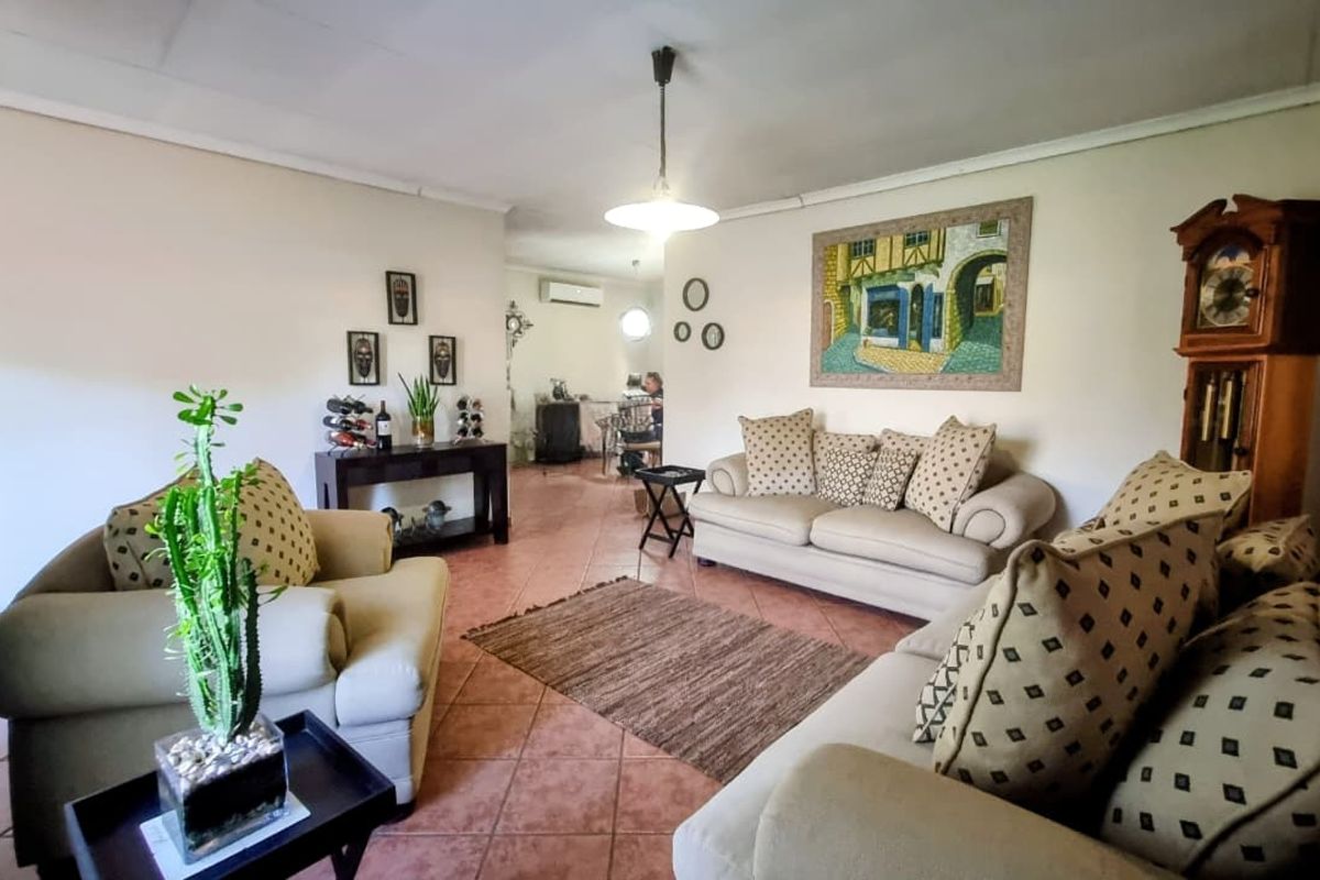 A spacious living room featuring terracotta floor tiles, a split-system air conditioning unit, and neutral wall finishes, offering a comfortable and functional living space.