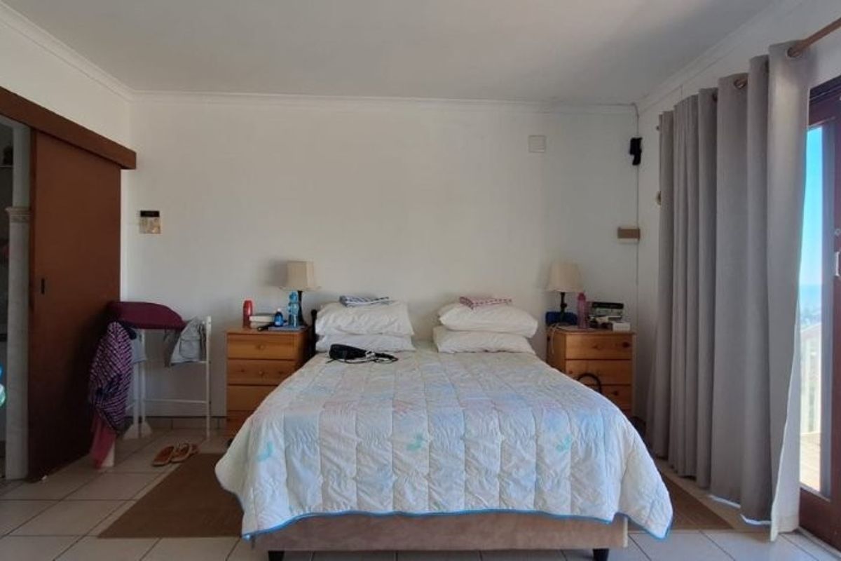 Bedroom featuring tiled flooring, a sliding door leading to an en-suite, and direct access to a balcony with ocean views.