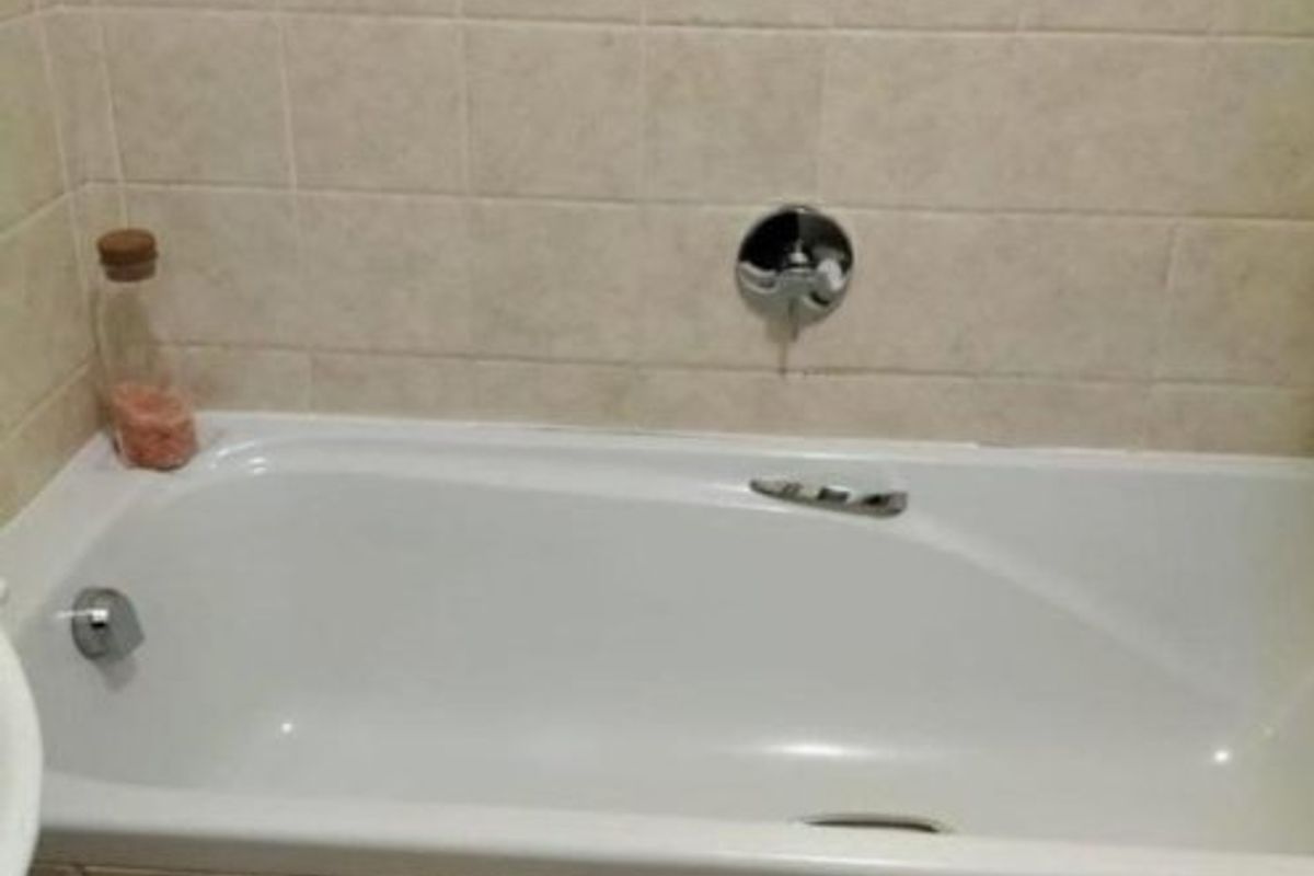 A standard bathroom featuring a built-in bathtub with tiled surround and chrome fixtures.