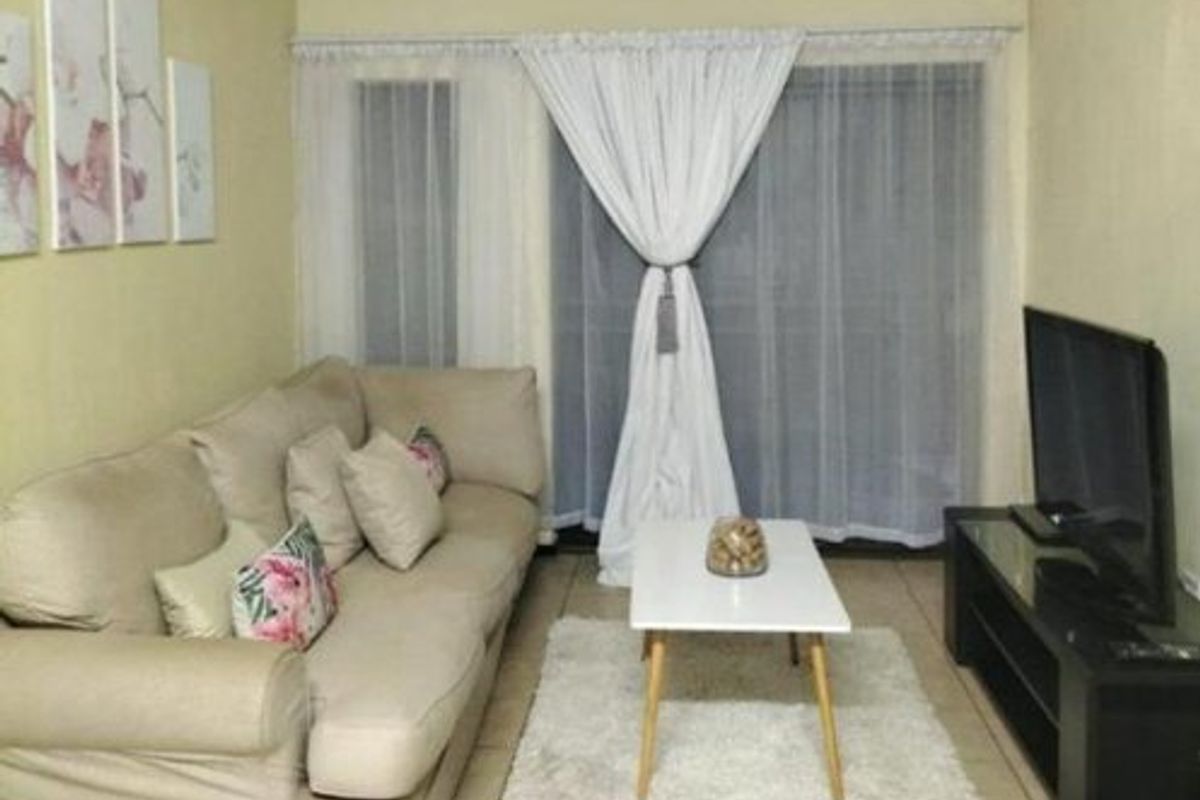 A living room area featuring tiled flooring and a sliding glass door providing natural light.