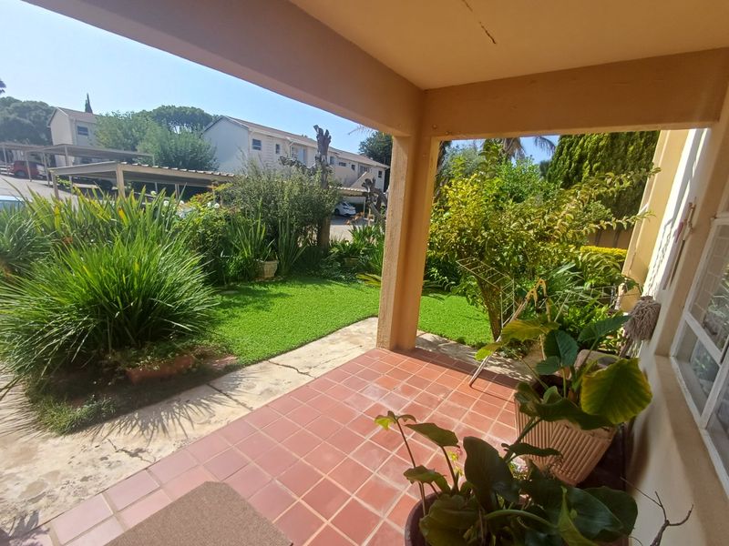 A covered patio area with tiled flooring, overlooking a private garden space.