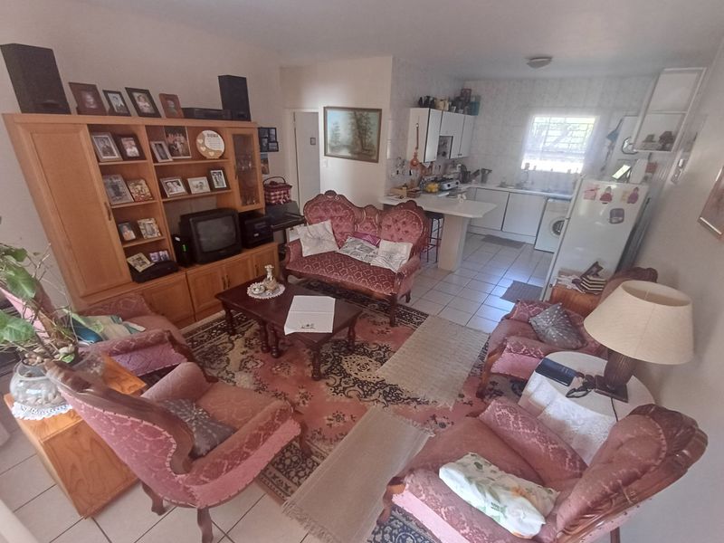 Open-plan living area featuring a combined lounge and kitchen space with tiled flooring and functional cabinetry.