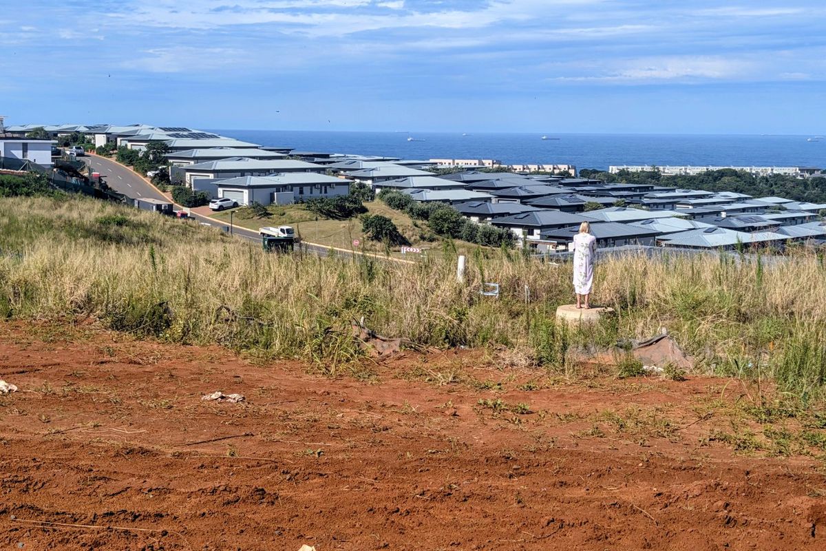 Elevated view overlooking a residential estate with coastal scenery in the background.