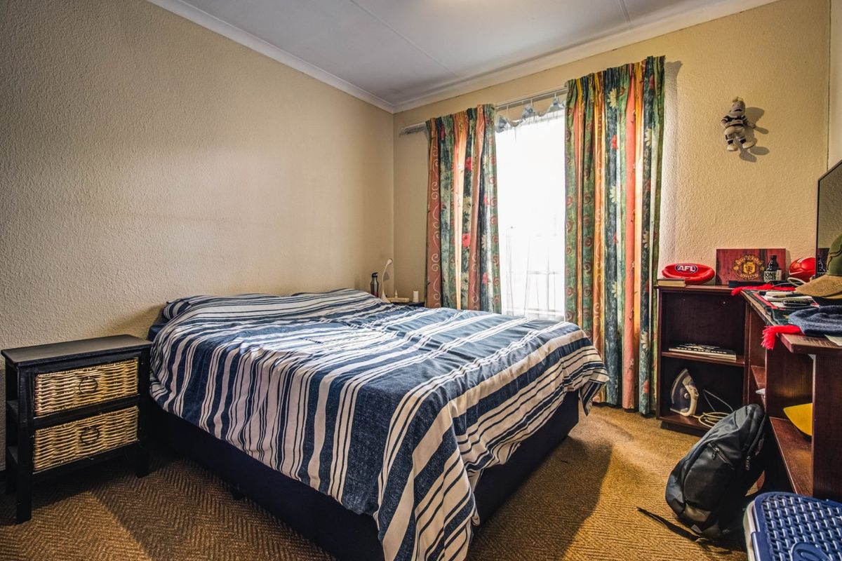 A functional bedroom featuring carpeted flooring and a window with curtain treatments, offering a neutral base for potential updates.