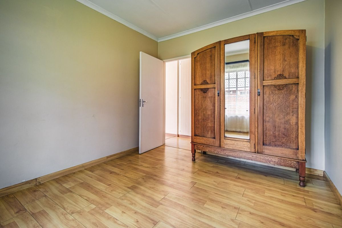 A bedroom featuring light-toned laminate flooring and neutral wall finishes, providing a clean and functional space.