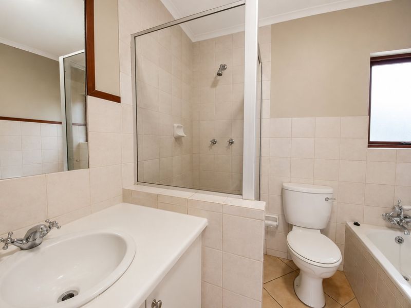 A functional bathroom featuring a built-in vanity, a glass-enclosed shower, a standard toilet, and a bathtub with chrome fixtures.