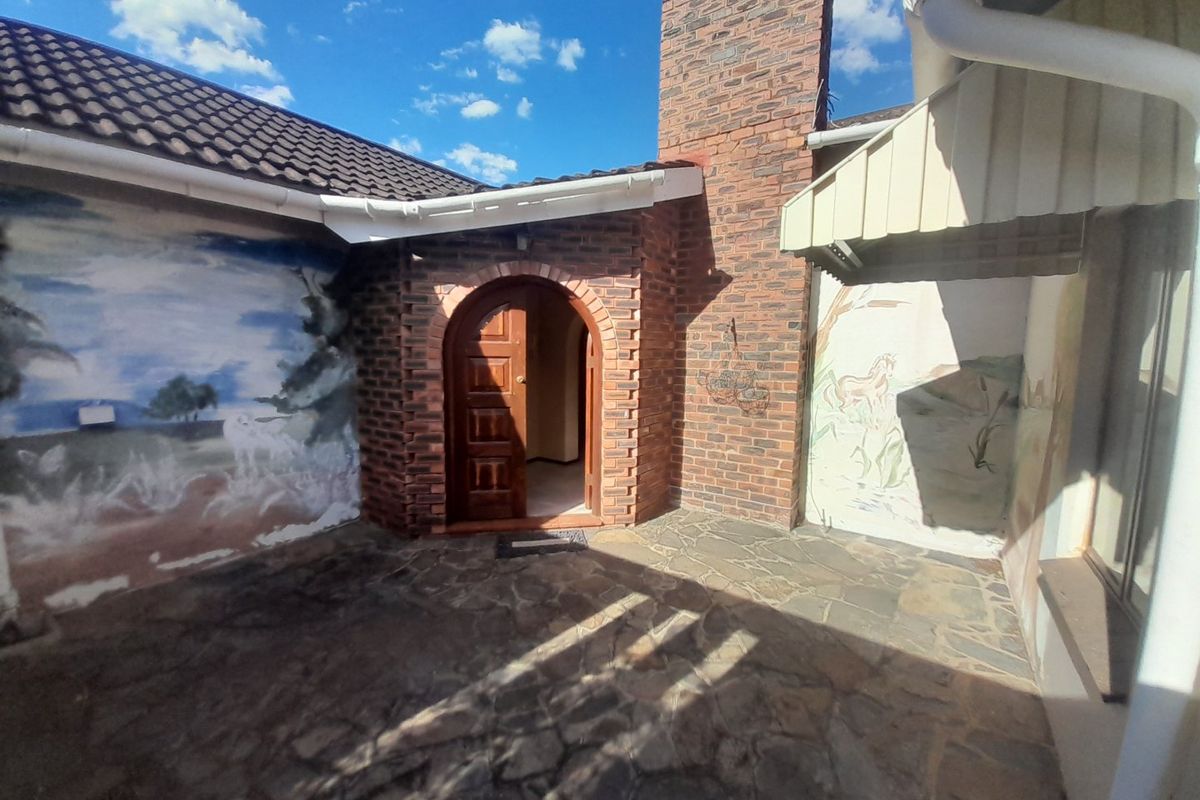 A private rear patio area featuring stone paving, a brick chimney, and an arched entrance door, offering a secluded outdoor space.