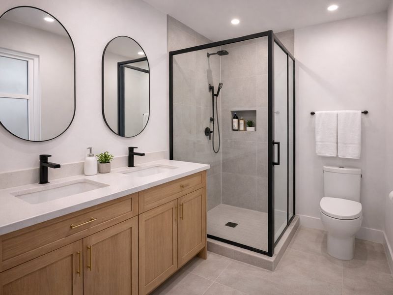 Modern bathroom featuring a double vanity with quartz countertops, a walk-in shower with black fixtures, and a wall-mounted toilet.