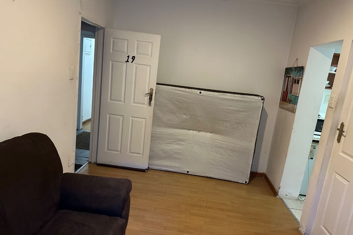 A living area featuring laminate flooring and internal doors, currently vacant and requiring minor cosmetic updates to improve the overall presentation.