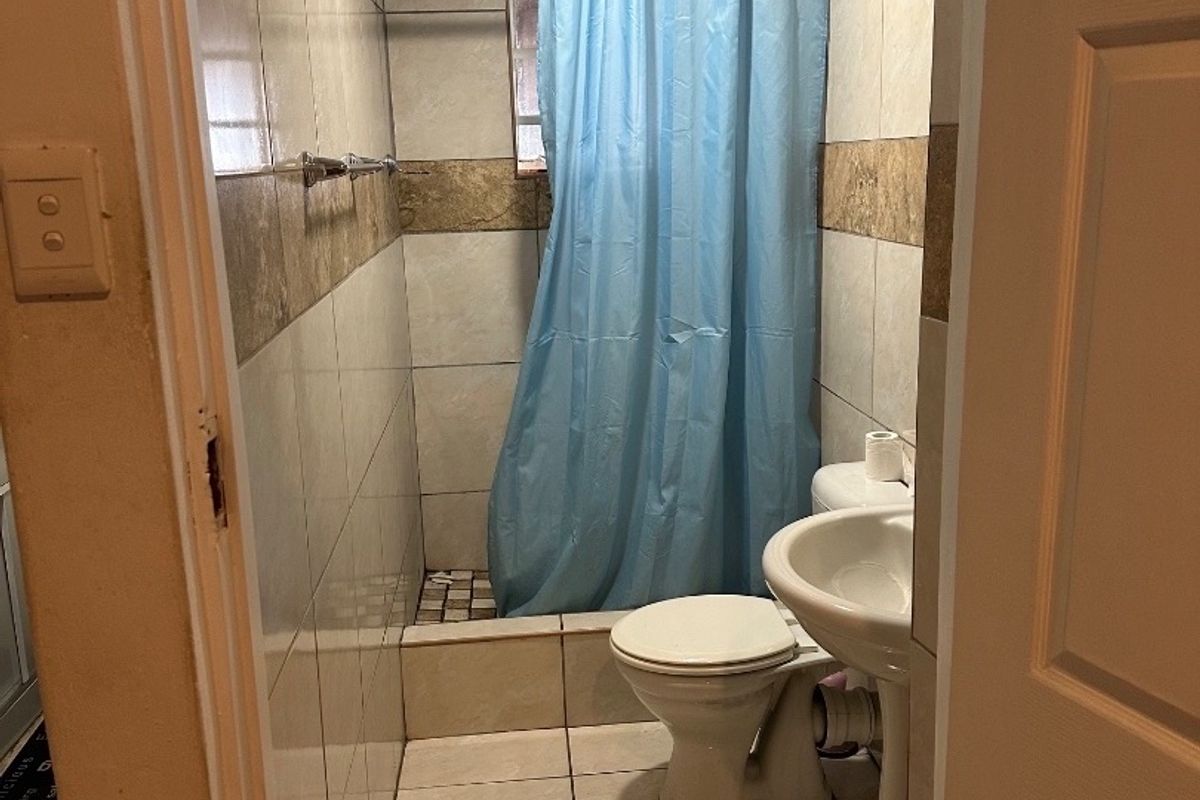 A compact bathroom featuring a pedestal basin, toilet, and a shower area with tiled walls and flooring.