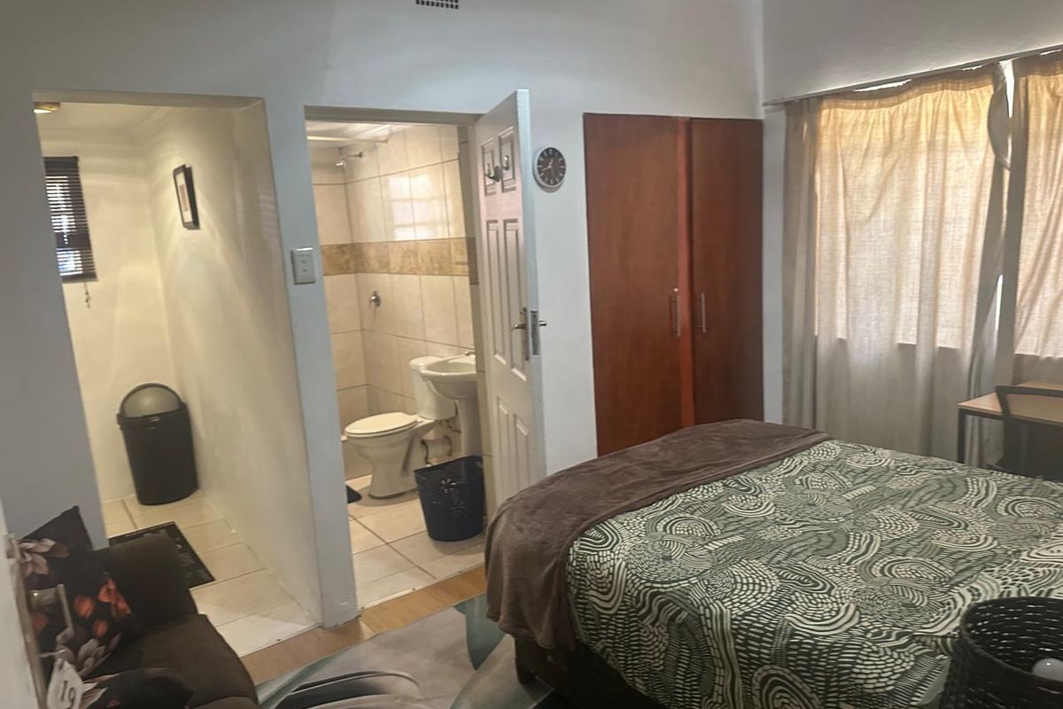 A bedroom featuring a built-in wardrobe and an attached en-suite bathroom with tiled finishes.