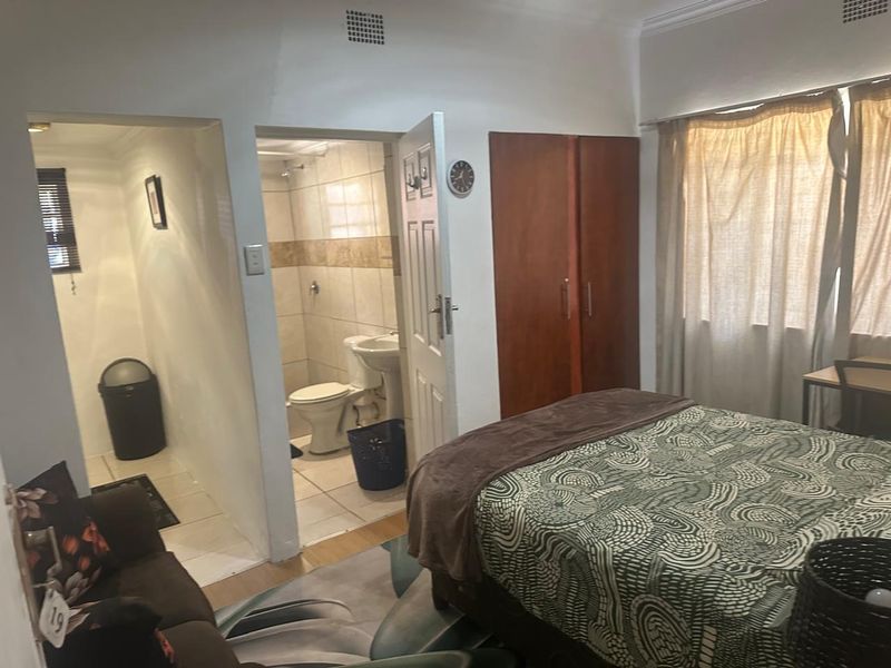 A bedroom featuring a built-in wardrobe and an attached en-suite bathroom with tiled finishes.