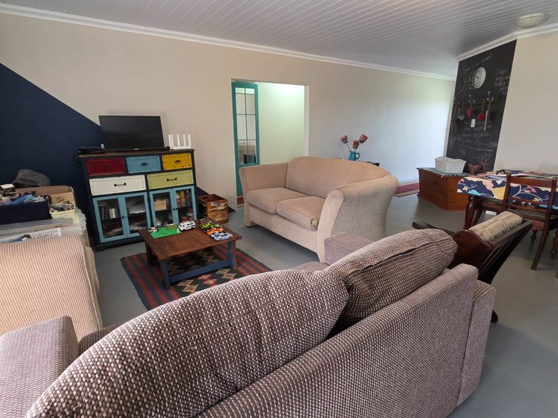 Spacious open-plan living and dining area featuring painted concrete floors, a unique chalkboard feature wall, and a classic tongue and groove ceiling.