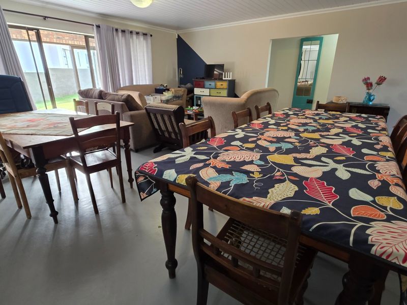 Spacious open-plan living and dining area featuring painted concrete floors, tongue and groove ceiling, and large sliding glass doors leading to the exterior.