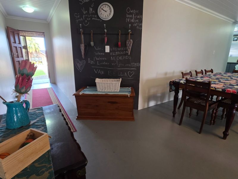 Open plan living and dining area featuring a chalkboard feature wall, painted concrete floors, and direct access to the exterior entrance.