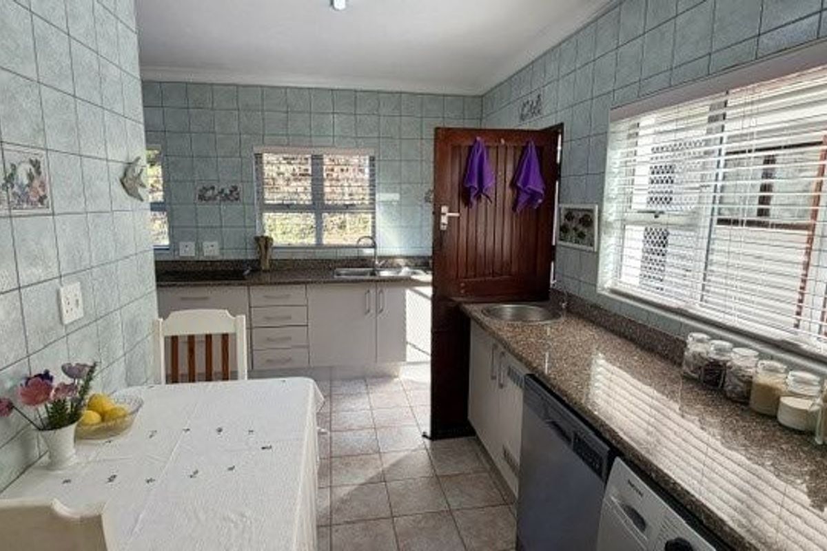 A functional kitchen featuring granite countertops, tiled wall finishes, and ample built-in cabinetry, providing a practical workspace with natural light.