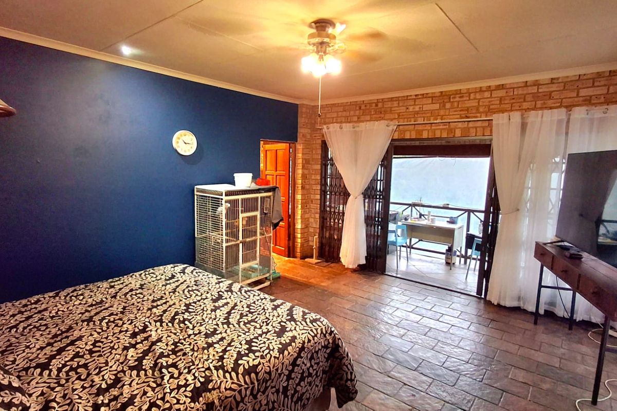 Spacious bedroom featuring exposed brick walls, tiled flooring, and direct access to an outdoor patio through sliding glass doors.
