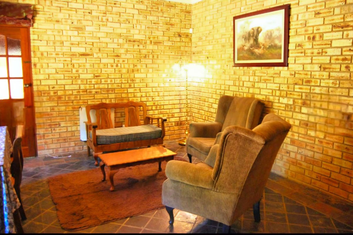 A rustic living room featuring exposed brick walls and dark tiled flooring, creating a warm and traditional atmosphere.