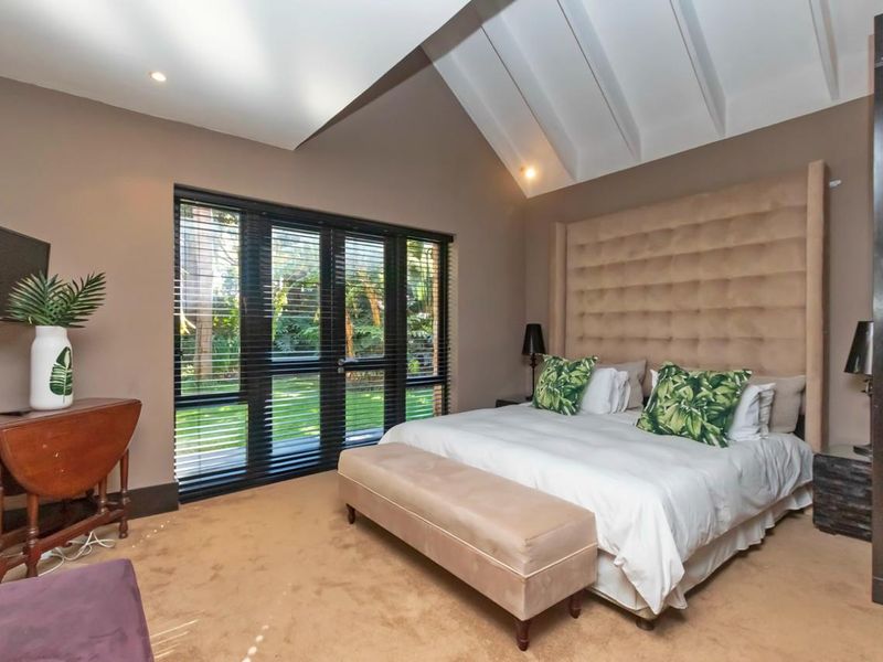 Spacious bedroom featuring a high vaulted ceiling, recessed lighting, and large glass doors providing direct access to the garden.