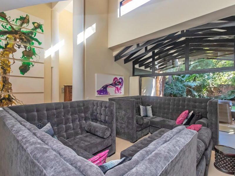 Spacious living area featuring double volume ceilings, exposed timber beams, clerestory windows, and large sliding doors providing seamless access to the garden.